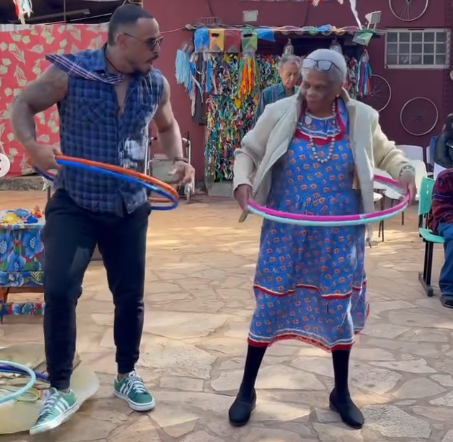 Voluntário e idosa brincando com bambolê